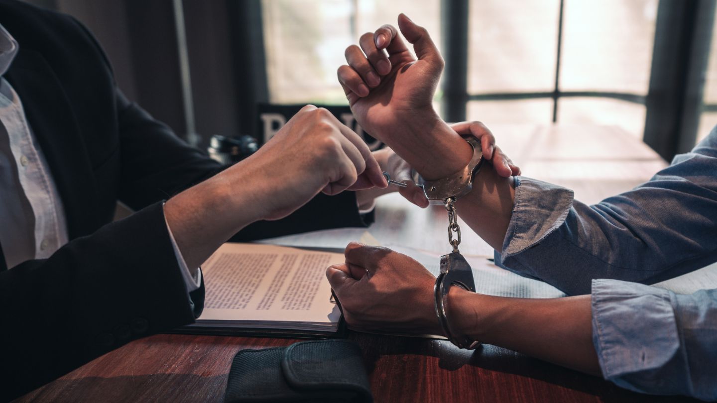 Handcuffed Person Sitting At Table